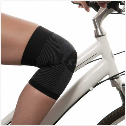 KS7 knee compression sleeve shown on person riding a bike.  Shaped-to-fit design conforms to your knee, allowing natural bending without bulky folds 